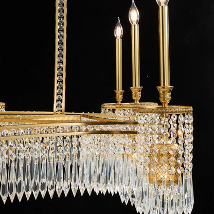 Detailed macro shot of ornate brass arms, cylindrical crystal shades, and glowing bulbs.