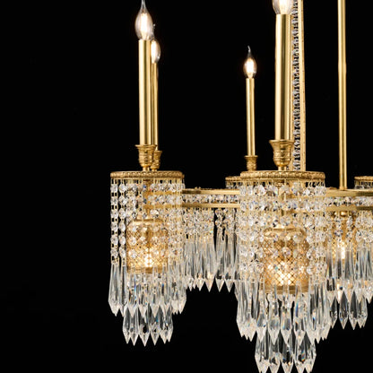 Macro shot of candle bulbs, crystal teardrops, and intricate brasswork on a hotel chandelier.