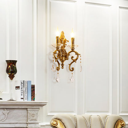 European castle-style brass wall lamp installed on white wainscoting beside a marble fireplace and books.