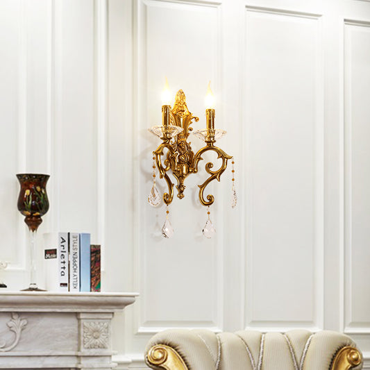 European castle-style brass wall lamp installed on white wainscoting beside a marble fireplace and books.