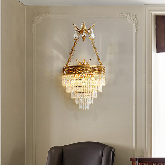 Close-up front view of the ornate French brass wall lamp with intricate scrollwork and a waterfall of crystal beads.