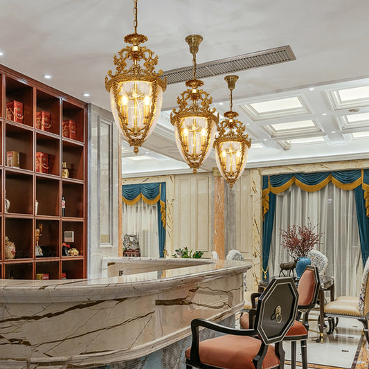 Three JEWELLERY TOP brass cage pendant lights installed above a marble bar in an elegant interior.