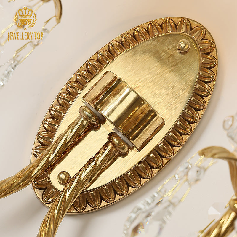 Detailed macro view of the sconce’s oval backplate featuring intricate radial petal engraving and polished brass finish.
