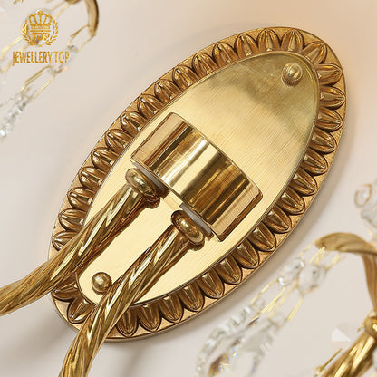 Detailed macro view of the sconce’s oval backplate featuring intricate radial petal engraving and polished brass finish.