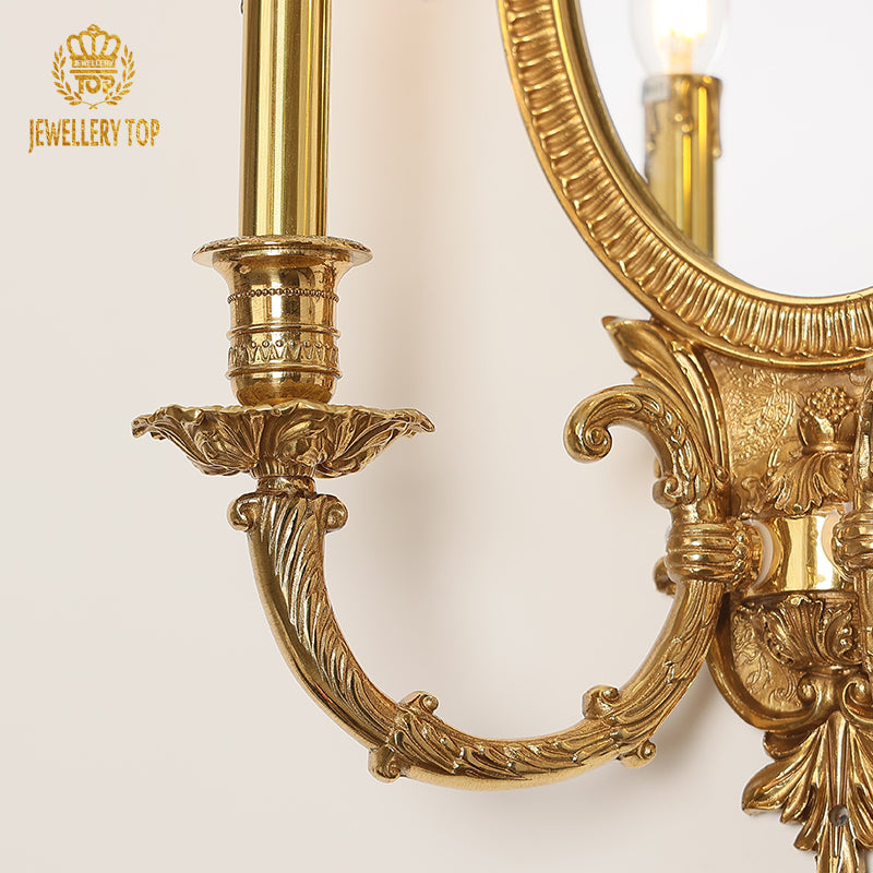 Macro shot focusing on the ornate brass bow decoration with a central floral accent atop the mirror sconce.