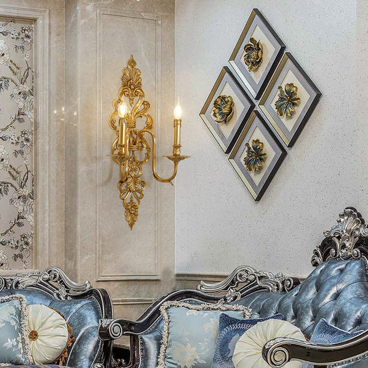 The Victorian-style brass wall lamp installed on a light textured wall beside decorative diamond-shaped artwork and a blue sofa.