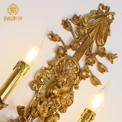Extreme close-up macro detail of the sconce’s central brass bow decoration and surrounding leaf motifs.