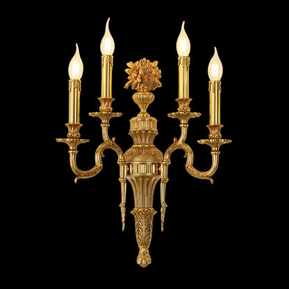 Triomphe Lys three-light golden brass wall sconce with ornate floral centerpiece, isolated on a black background.