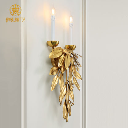 Front product view of the ornate brass sconce showcasing its pendant leaf cluster and classic candle-style bulb holders.
