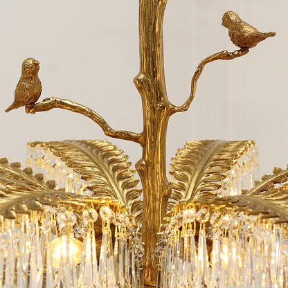 Detailed view of brass bird figurines and feather-like leaves on a crystal chandelier.