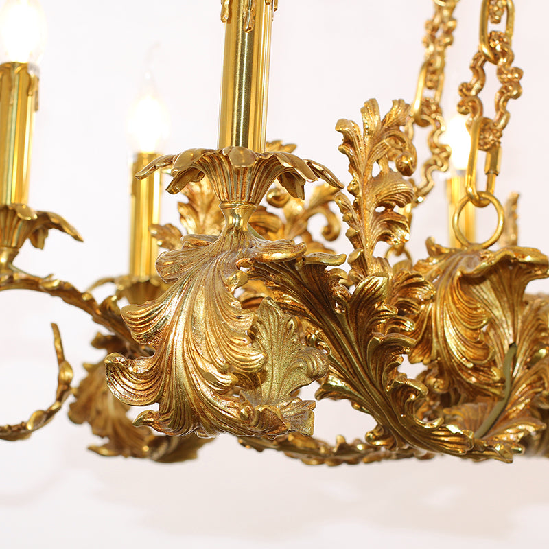 hand carviExtreme close-up macro of detailed brass leaf scrollwork and a glowing candle bulb.ng lamp arms pure brass chandelier