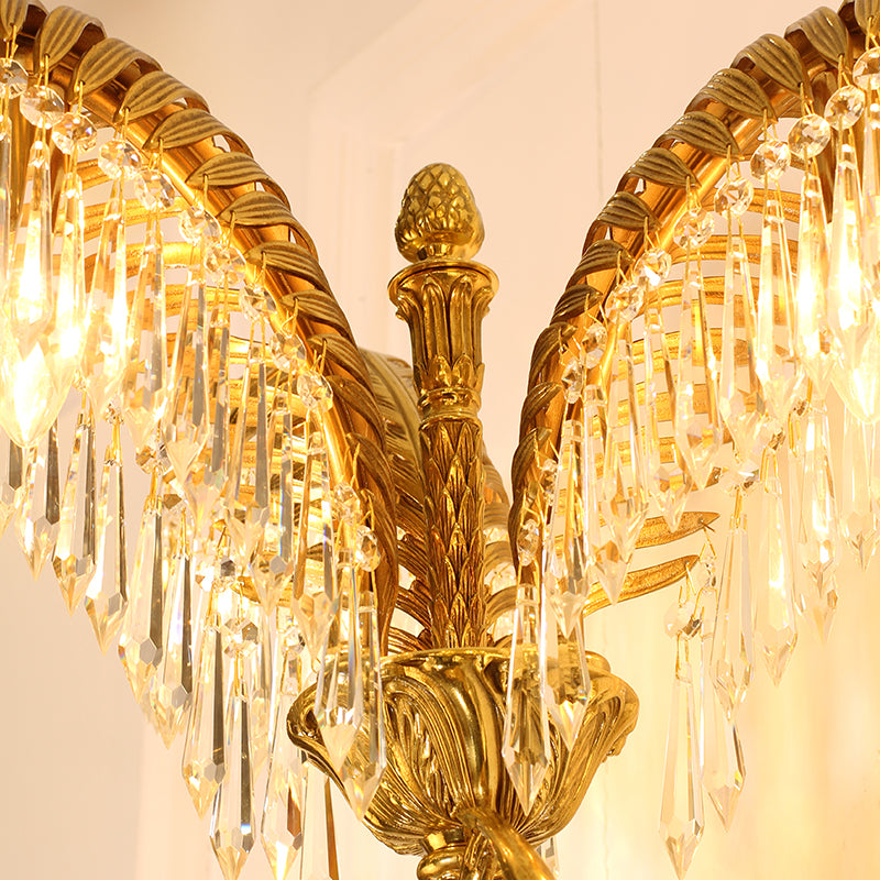 Macro shot of a single, intricately textured brass palm leaf adorned with sparkling clear crystal droplet pendants.