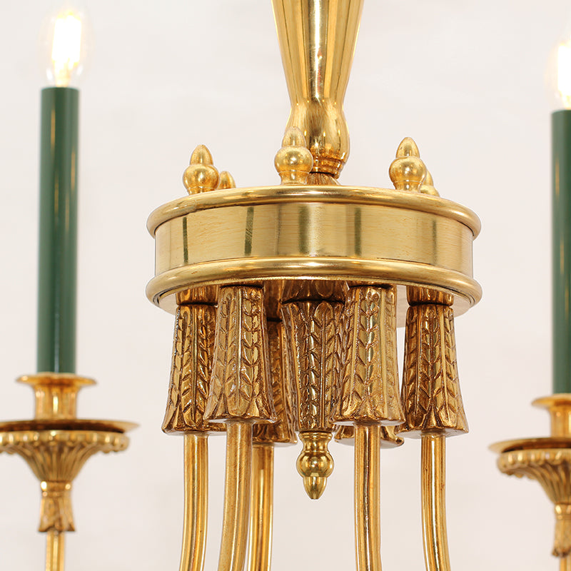 Extreme close-up of the central brass column with textured seed carvings and green candle lights.
