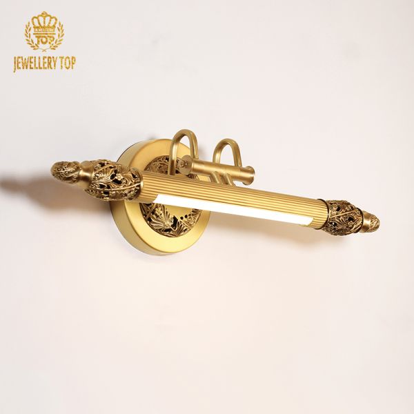 Close-up detail of the pierced floral filigree and acanthus leaf design on the brass end ball of the sconce.