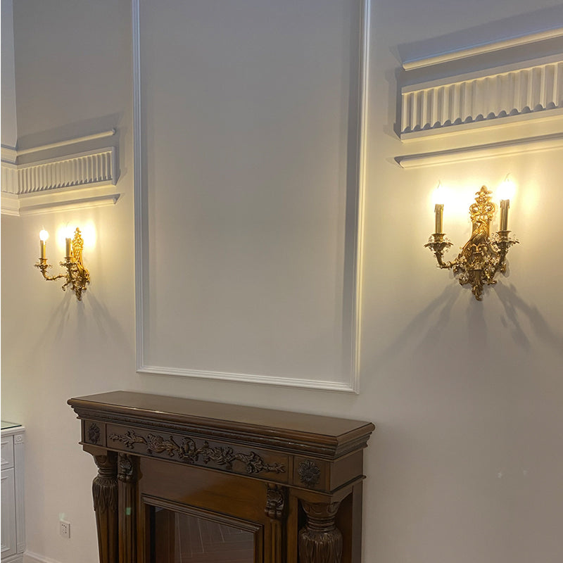 A pair of the ornate French brass wall lamps installed symmetrically on a white wall with glass shades.
