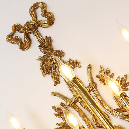 Close-up macro detail of the ornate brass bow, vine, and leaf decorations on the wall light.