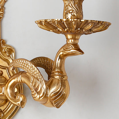 Detailed view of the brass sconce’s ram’s horn curl design and polished surface against a white background.