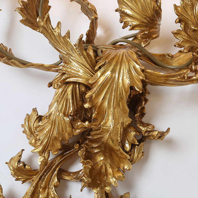 Extreme close-up macro detail of the sconce’s Baroque-style fan-shaped brass leaves with intricate surface texture.