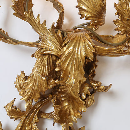 Extreme close-up macro detail of the sconce’s Baroque-style fan-shaped brass leaves with intricate surface texture.