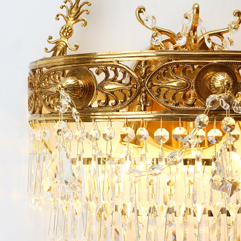 Macro detail of the hand-strung faceted crystal pendants and the polished brass arm of the wall light.