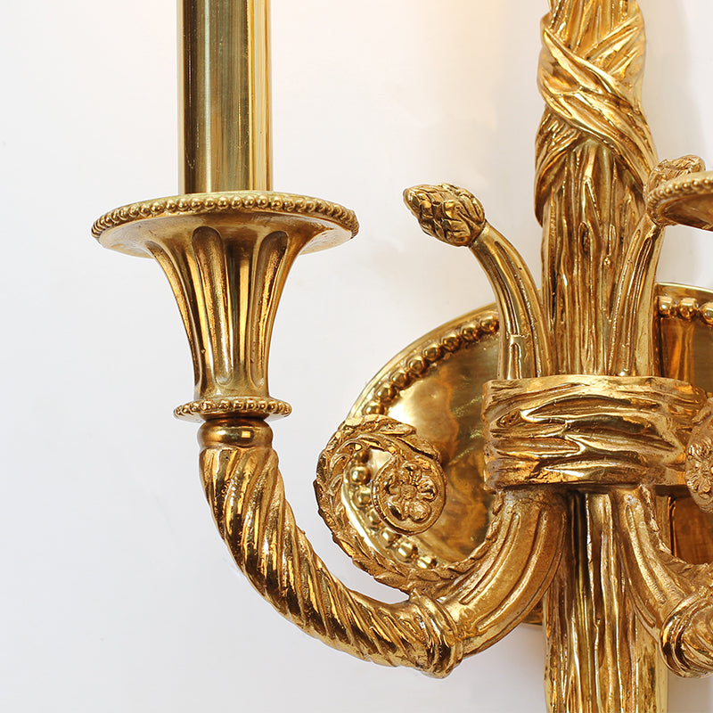 Focus on the ornate scrollwork arm and the frosted glass candle-style bulb of the classic brass light.