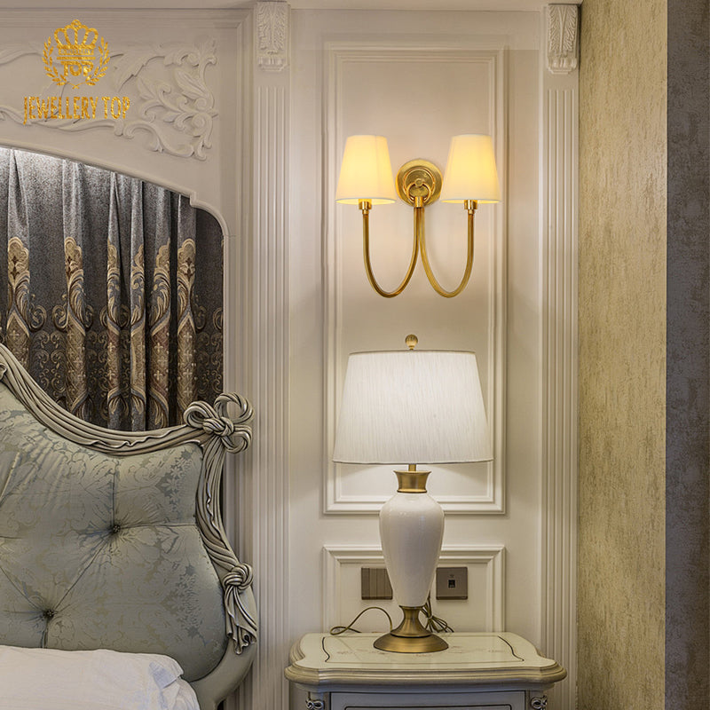 The European decorative wall sconce installed in an elegant bedroom setting with a carved headboard and side table.