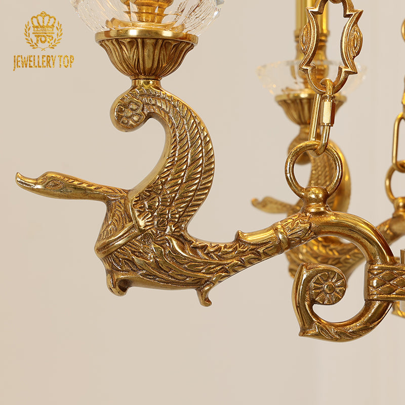 Detailed shot of an ornate brass bird figurine and crystal shade on the chandelier.
