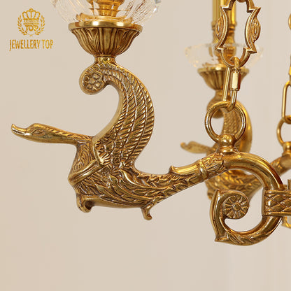 Detailed shot of an ornate brass bird figurine and crystal shade on the chandelier.