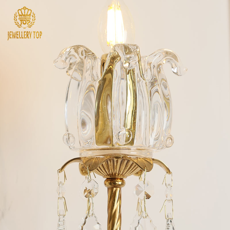 Extreme close-up of the tulip glass shade, glowing bulb, and sparkling crystal droplet fringe on the luxury wall light.