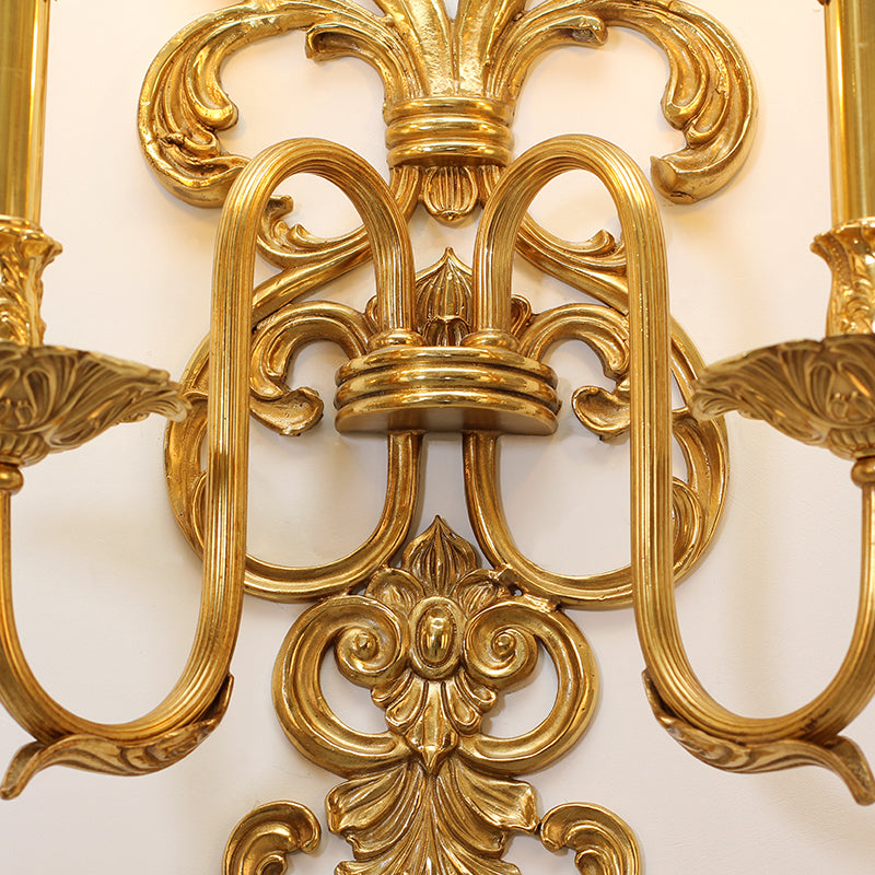 Extreme macro detail of the central intricate floral and scroll engraving on the golden hotel wall light.