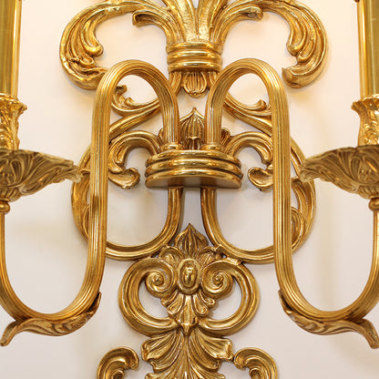 Extreme macro detail of the central intricate floral and scroll engraving on the golden hotel wall light.