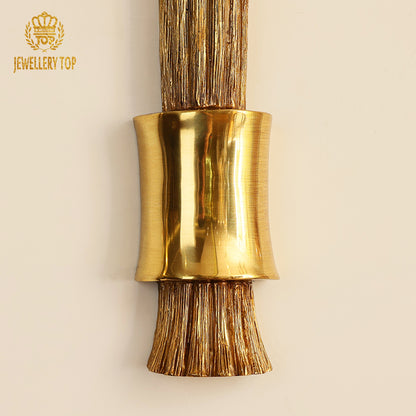 Detailed close-up of the brass wall lamp's fluted stem and connection to its textured circular base.