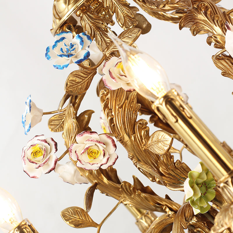 Macro close-up of hand-painted ceramic roses and leaves on a French brass chandelier arm.