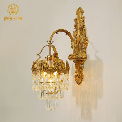 Close-up detail of the ornate brass wall sconce, showcasing intricate leaf scrollwork and sparkling crystal droplets.