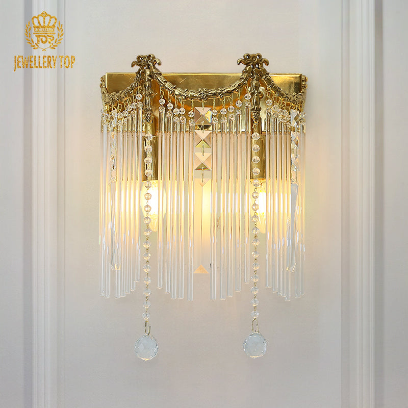 The luxury crystal wall light installed on a white wall, showcasing its full cascading crystal design and JEWELLERY TOP branding.