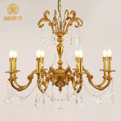 Front view of a JEWELLERY TOP branded brass crystal chandelier against a light wall.
