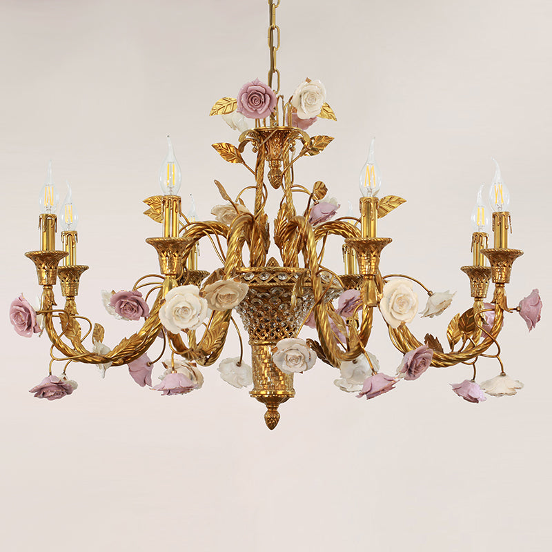 A decorative brass chandelier featuring a crystal basket and clusters of ceramic blossoms.