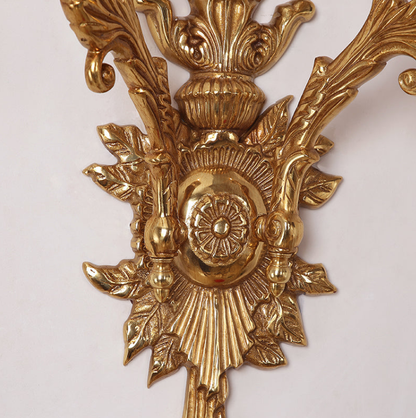 Macro shot of the ornate brass finial, leaf decorations, and textured surface of the French sconce.