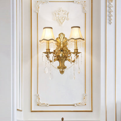JEWELLERY TOP luxury brass wall lamp with detailed metalwork and crystal chains, mounted on a white wall.