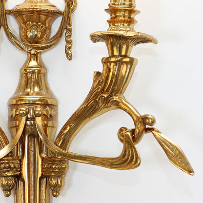 Extreme close-up of the sconce’s polished brass arm, showcasing its fluted texture and crafted connection points.
