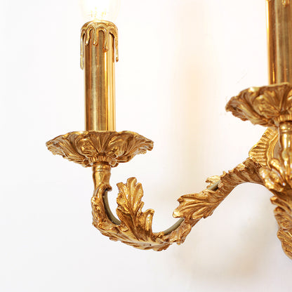 Extreme close-up of a candle-style bulb holder with drip-texture and intricate metal leaf engraving.