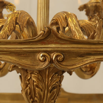 Extreme close-up of intricate brass scrollwork and “JEWELLERY TOP” branding on a pendant light.