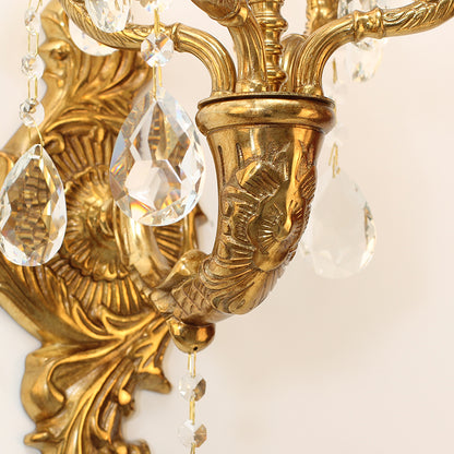 Extreme close-up of a curved brass arm, textured patina, and hanging strands of sparkling crystal pendants.