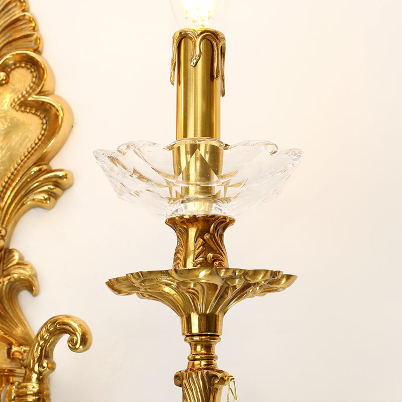 Detailed shot of a candle bulb, glass tray, and sparkling crystal pendants on the brass home decor sconce.