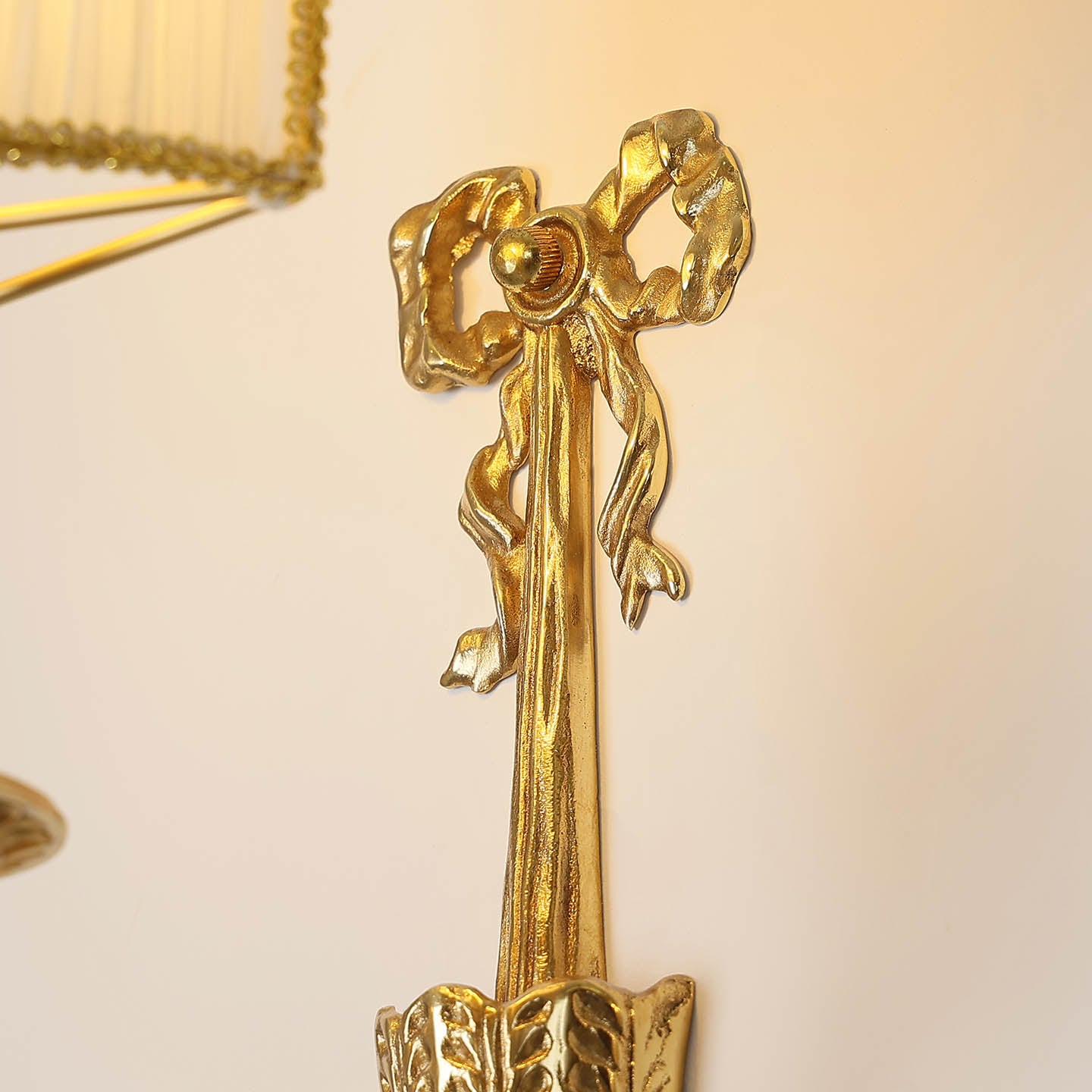 Extreme close-up macro detail of the sculpted brass ribbon bow with realistic folds and polished surface texture.