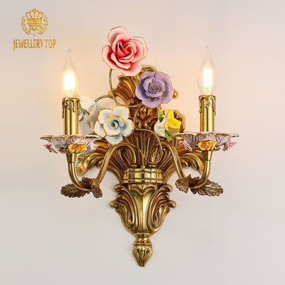 JEWELLERY TOP Jardin de Porcelaine brass wall lamp with colorful ceramic flowers and two candle lights on a white wall.