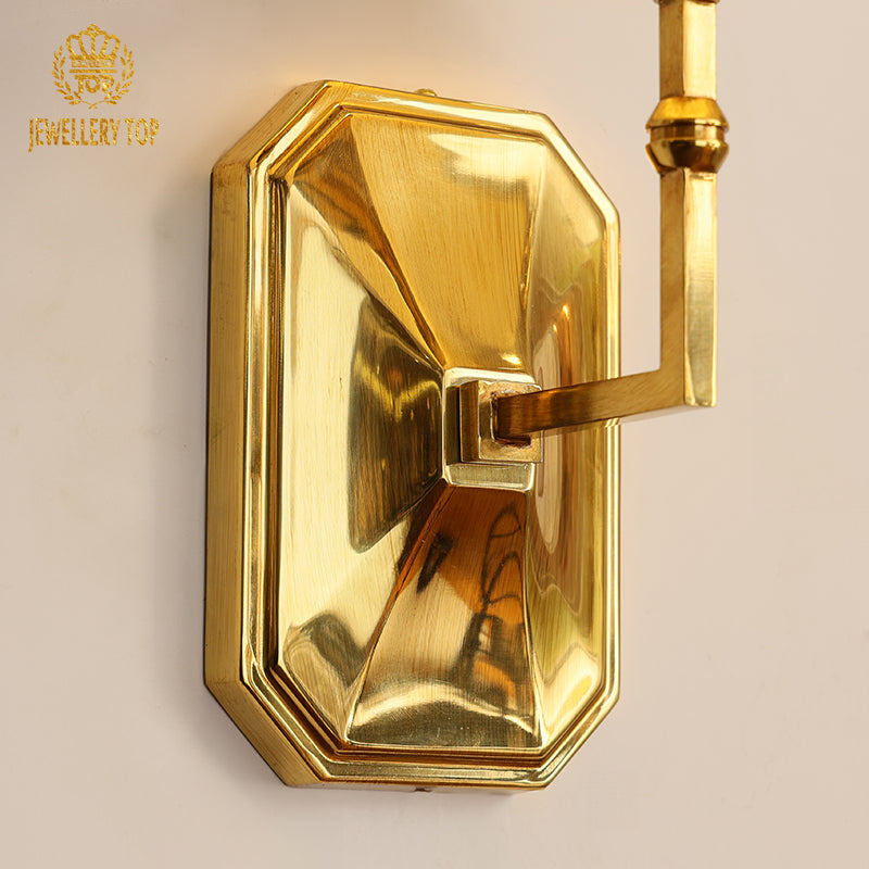 Branded product image (JEWELLERY TOP) of the wall light, focusing on the textured backplate and warm illumination.