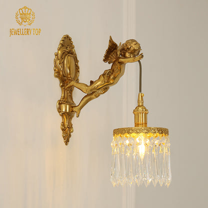 Close-up front view of the ornate antique brass sconce with a flying angel figure and glowing bulb.