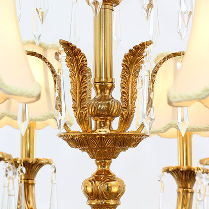 Macro close-up of a brass arm with leaf engraving, a pleated fabric shade, and hanging crystal prisms.