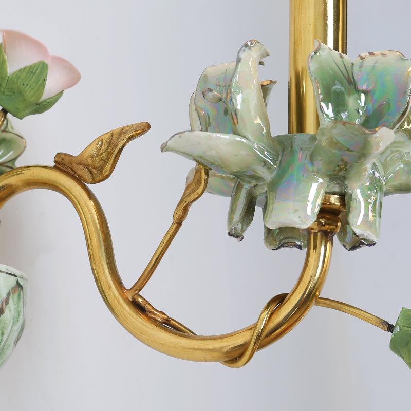 Detailed view of the brass arm’s polished finish and its connection to the ceramic floral arrangement.